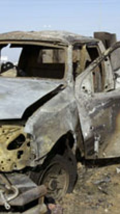 Iraqi policeman looks at blown-up car