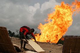 A local Nigerian boy dries tapioca a local cassava meal close to a gas flare in the Niger Delta