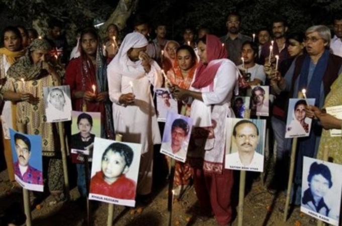 A riot survivor, centre left wearing white, breaks down as others hold candle during a candlelit vigil to mark the 10th anniversary of the Gujarat riots as photographs of riot victims stand in the foreground in Ahmadabad, India, on February 24, 2012 [EPA]