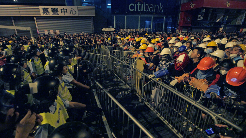 Protestors don hard hats and improvised arm guards to protect themselves from police batons [Lee Xian Jie / Al Jazeera]