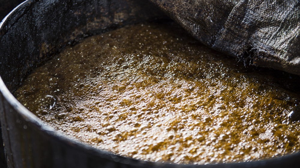 Having been left to ferment, the sticky liquid is ready to be distilled [AJ Heath/Al Jazeera]