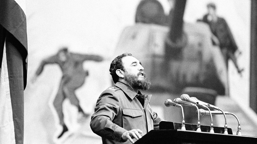 Fidel Castro speaks in 1981 of Cuba's victory at the Bay of Pigs with a painting in the background showing him jumping from a tank [AP]