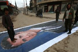 Fighters from a coalition of Islamist forces stand on a huge portrait of Syrian President Bashar al-Assad in Idlib [AFP]