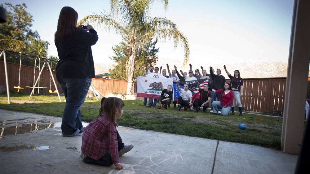 Jeff Hall’s wife Krista takes a picture of National Socialist Movement members as they chant and make Sieg Heil gestures in the garden of her home in Riverside, California.  [Julie Platner]