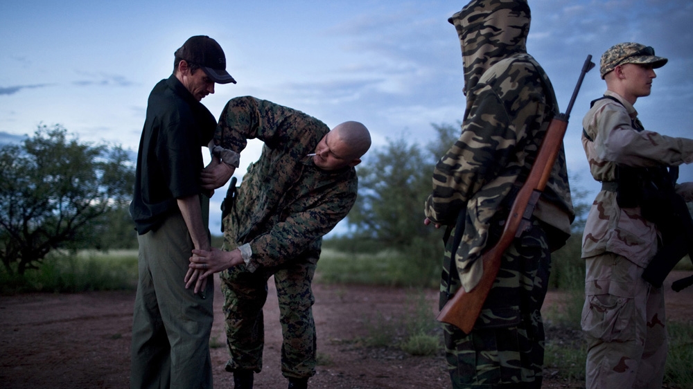 Jeff Hall shows another National Socialist Movement member how to pull a knife from his waist band as they prepare for a nighttime patrol along the US-Mexico border in Arivaca, Arizona. They intended to set up listening posts and hoped to catch immigrants crossing from Mexico. August 2010 [Julie Platner]