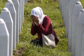 A woman prays near the grave of her relative, among 136 newly identified victims of the 1995 Srebrenica massacre lined up for a joint burial in Potocari