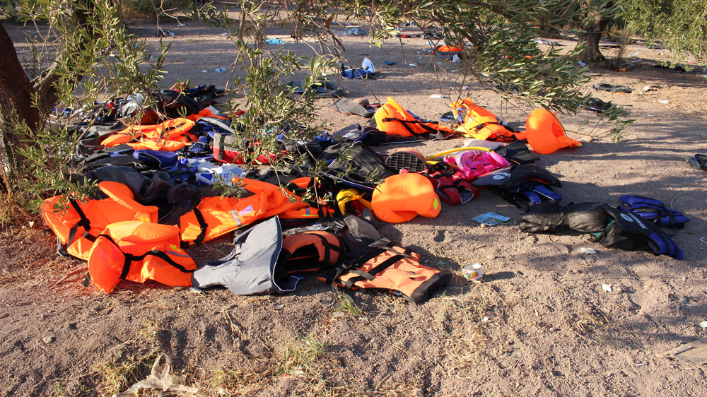Life vests damaged during a coastguard raid lie discarded under a tree at the refugee launching point on the Turkish coast [Kevin Kusmez/Al Jazeera]