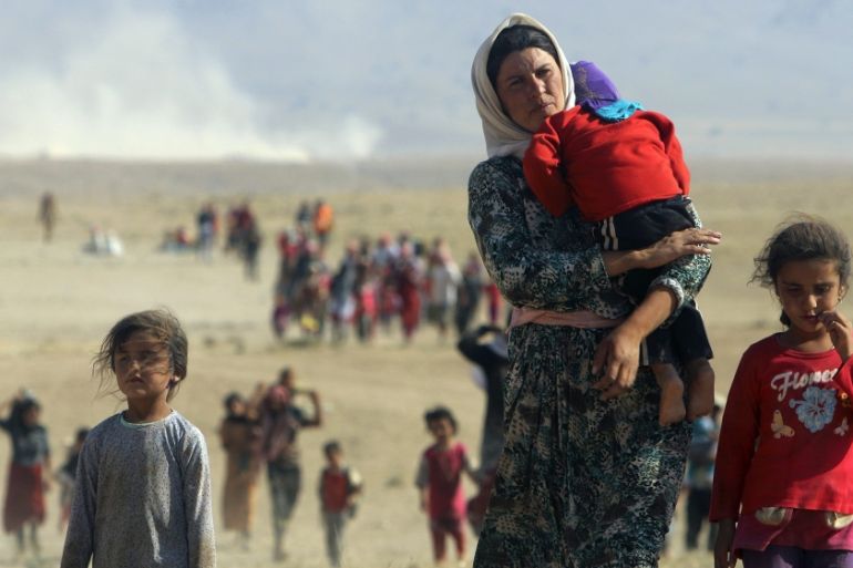 Displaced people from the Yazidi minority walk towards the Syrian border