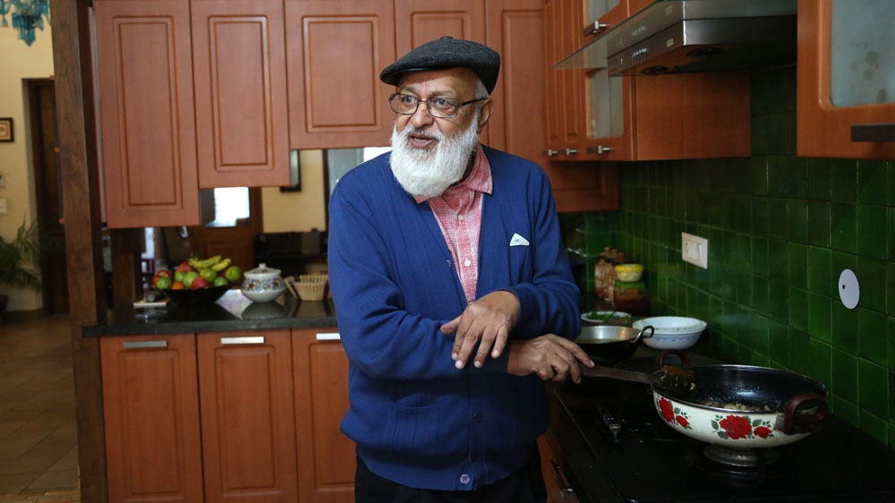 Pant, photographed in his home, tends to a dish of goat ishtoo - a name that is a nod to the word stew [Showkat Shafi/Al Jazeera]