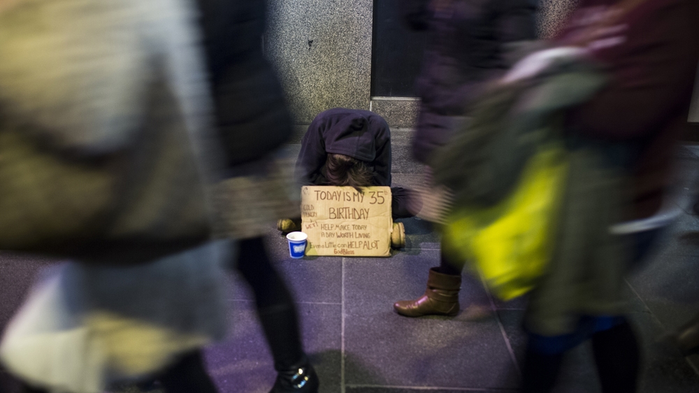 A homeless person begs on 5th Avenue in New York City, one of the busiest commercial streets in the city [Edu Bayer/Al Jazeera]