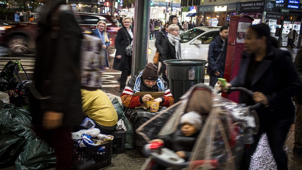 A homeless person begs on Avenue of the Americas and 32nd Street in New York City [Edu Bayer/Al Jazeera]