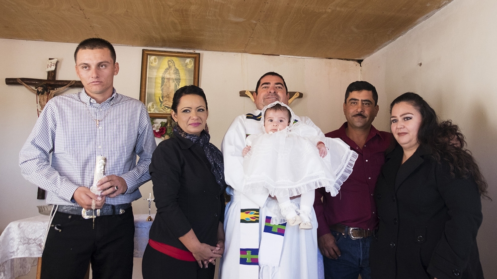 Prisciliano Peraza (holding the baby), drives around the countryside near the border with the United States every weekend, to wed, baptise and perform religious services for the criminal groups [Axel Storen Weden /Al Jazeera] 