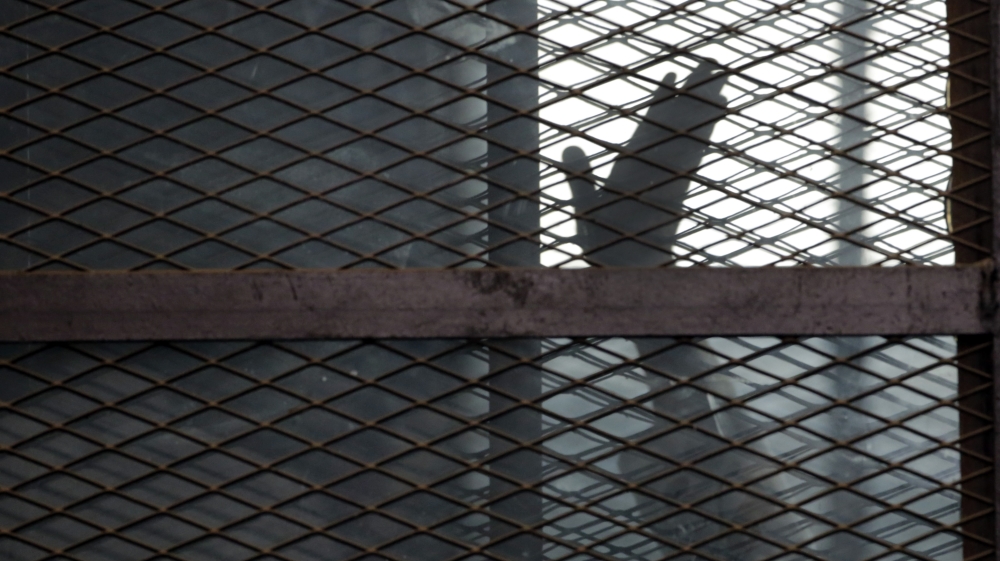 A Muslim Brotherhood member gestures from a defendants' cage in a courtroom in Torah prison in 2015 [File: Amr Nabil/AP]]