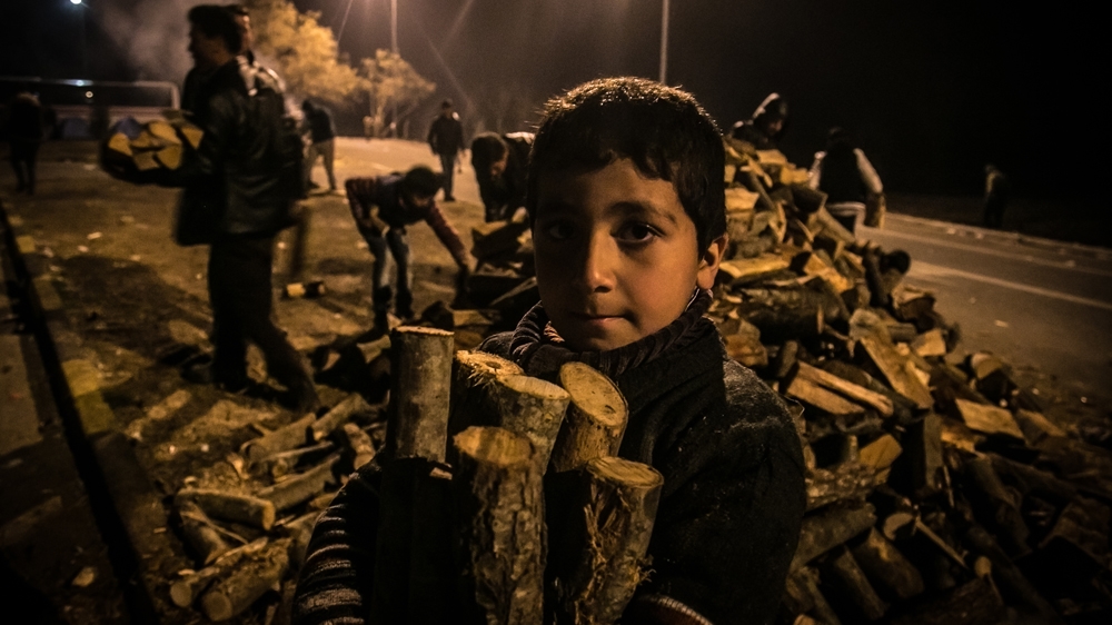 A child collects wood for the night at the petrol station of Polikastro, 20km from the Idomeni border, where thousands of people are stranded [Nicola Zolin/Al Jazeera]  