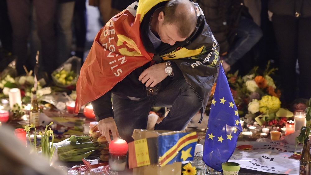  A man lights a candle at a memorial for victims of Tuesday's attacks [Martin Meissner/AP] 