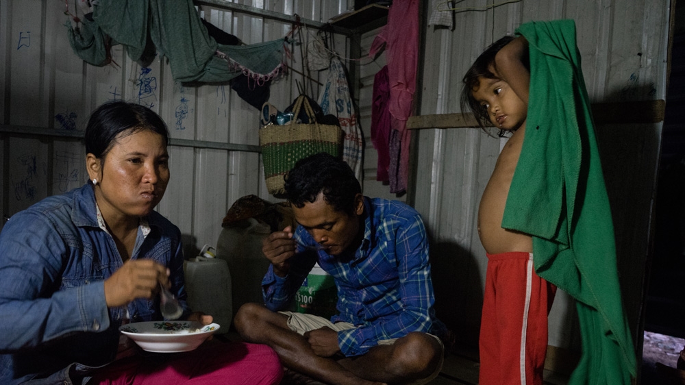 Chhorn Chunta, left, and her husband eat breakfast before going to work at a construction site in Phnom Penh [Hannah Reyes/Al Jazeera]
