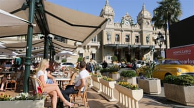 People sit at an outdoor cafe terrace as the Casino de Monte-Carlo stands beyond in Monaco [Getty] 