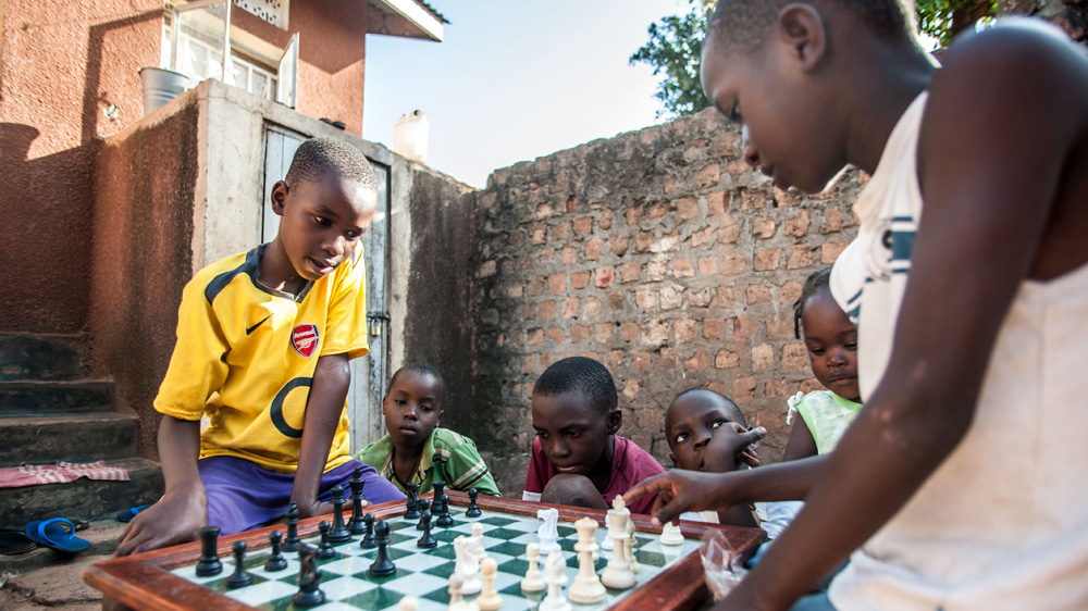Children gather to watch a chess match after school in Katwe, where much of the upcoming movie was filmed [Aurelie Marrier d'Unienville/Al Jazeera]