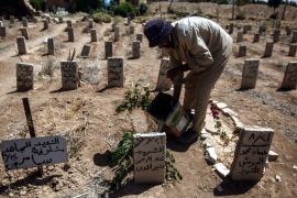 A worker in the cemetery of Douma drops some water and put a green branch on the tomb a volunteer who died while helping people in Zamalka during the chemical attack, Douma, in August 2016 [EPA]