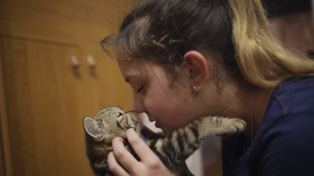 Diana Zakalova plays with her cat in her home in Makeevka. In her spare time she likes boxing and ballet [Kyrre Lien/Al Jazeera] 
