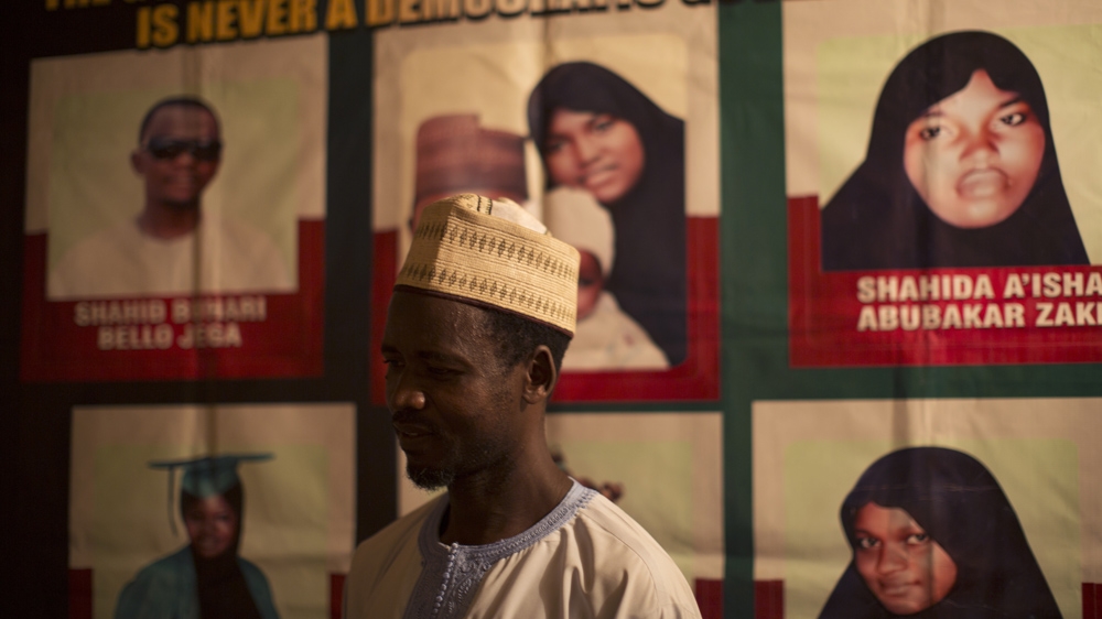 Abubakar Zaki in front of a poster showing some of el-Zakzaky's followers who were killed in December 2015 [Chika Oduah/Al Jazeera] 