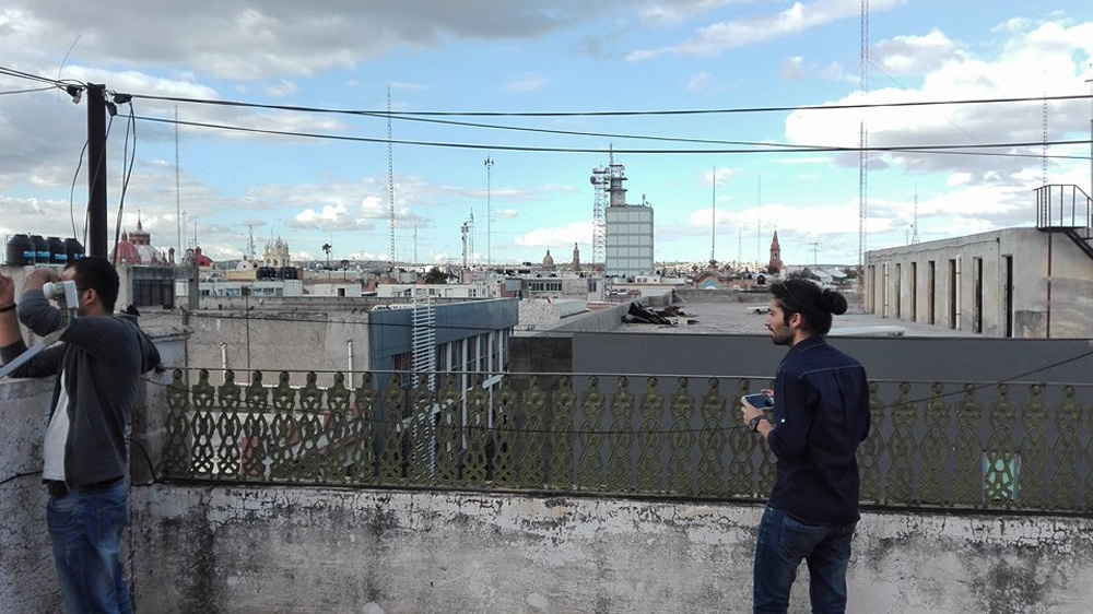 Zain and Hazem take photos from a friend's rooftop overlooking Aguascalientes, Mexico [Tim MacGabhann/Al Jazeera]