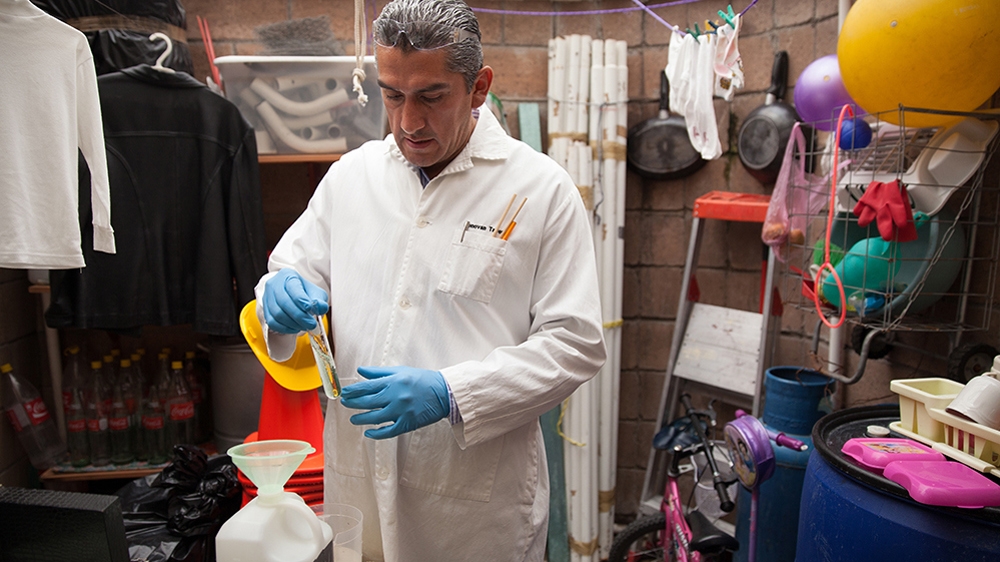 Donovan prepares one of the 370 formulas he devised - and memorised - in order to carry out his forensic cleaning in the utility room behind his kitchen [Benedicte Desrus/Al Jazeera]