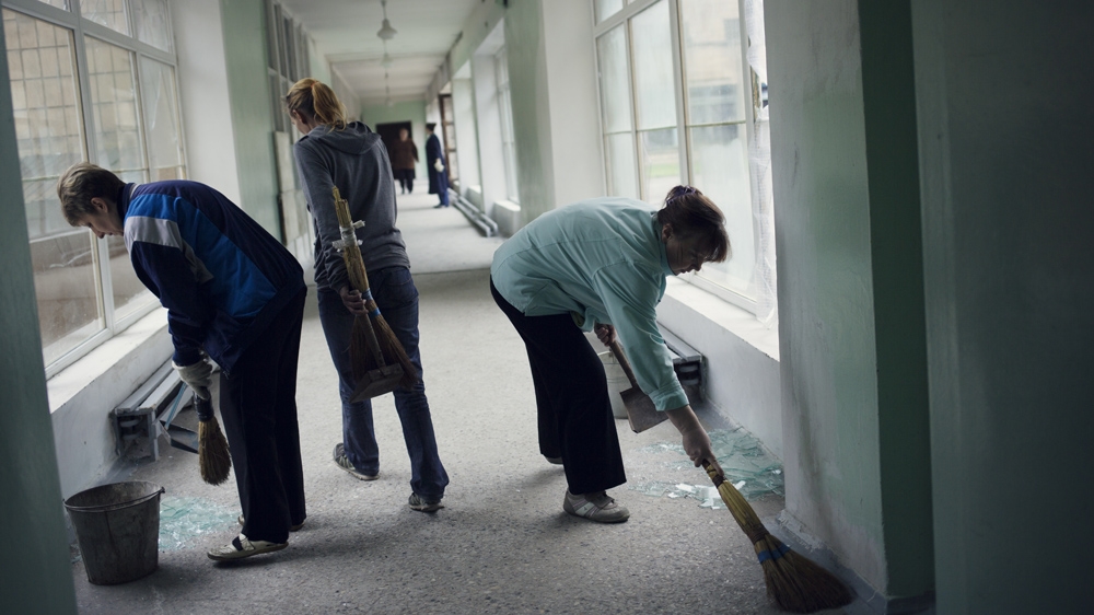 Teachers clean up broken glass. The day before, there was heavy shelling in Kievskaja and the school was hit. No one was killed, the Organization for Security and Co-operation in Europe said [Kyrre Lien/Al Jazeera] 