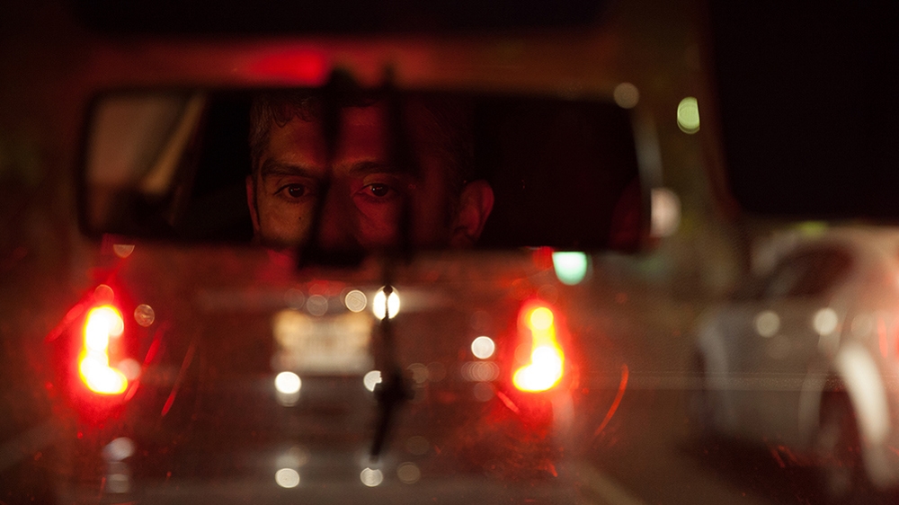 Donovan in the rear-view mirror of his car, late at night after giving his business cards to the city's detective units in Mexico City [Benedicte Desrus/Al Jazeera]