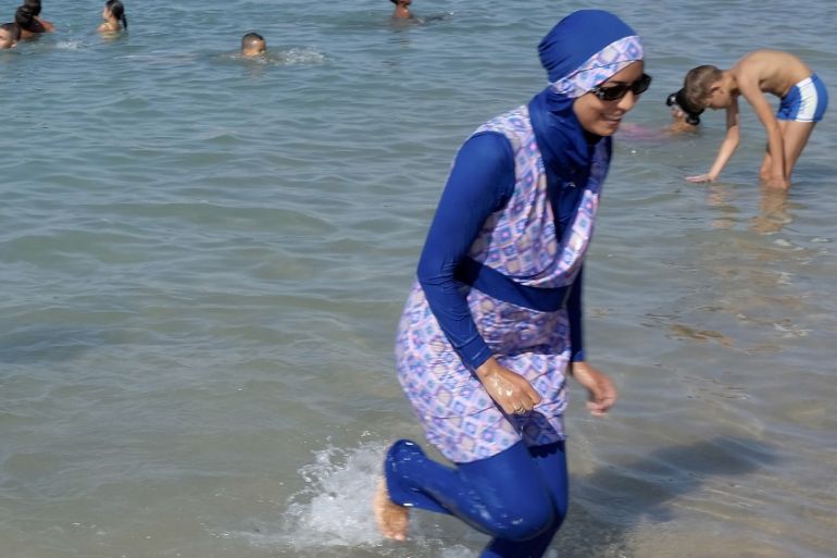 A woman wearing a burkini walks in the water on a beach in Marseille