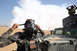 Iraqi forces wear gas masks for protection, as smoke billows in the background from al-Mishraq chemical plant [AFP]