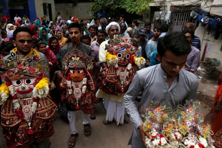 Hindu devotees hold the deities of lord Jagannath along with others during the Rath Yatra, or chariot procession in Karachi