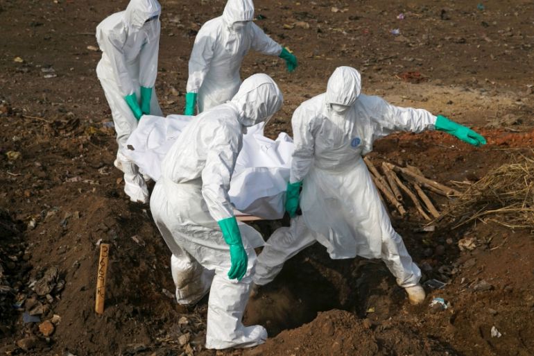 Health workers carry the body of a suspected Ebola victim for burial at a cemetery in Freetown