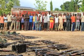 Suspected fighters are paraded before the media by Burundian police near a recovered cache of weapons after clashes in the capital Bujumbura