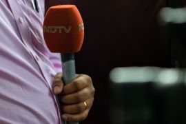 A news reporter with the Indian news channel NDTV holds a microphone.