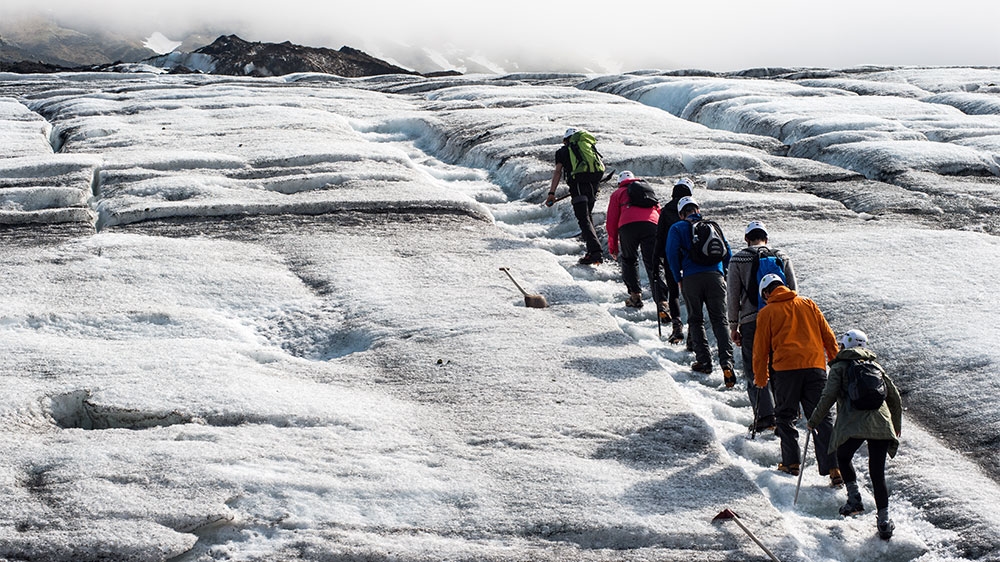 A tour group begin their ascent on to Falljokull glacier by following a route chopped into the ice by the guides. The glacier has been losing 35 metres in length every year since 2005 [Alexander Lerche/Al Jazeera]