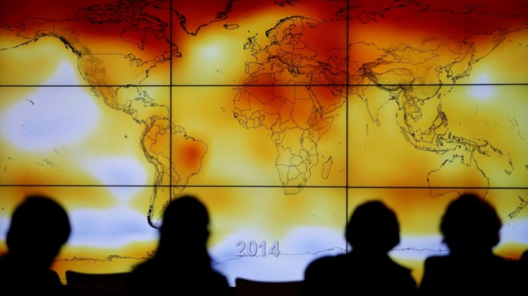 FILE PHOTO: Participants looks at a screen projecting a world map with climate anomalies during the World Climate Change Conference 2015 (COP21) at Le Bourget