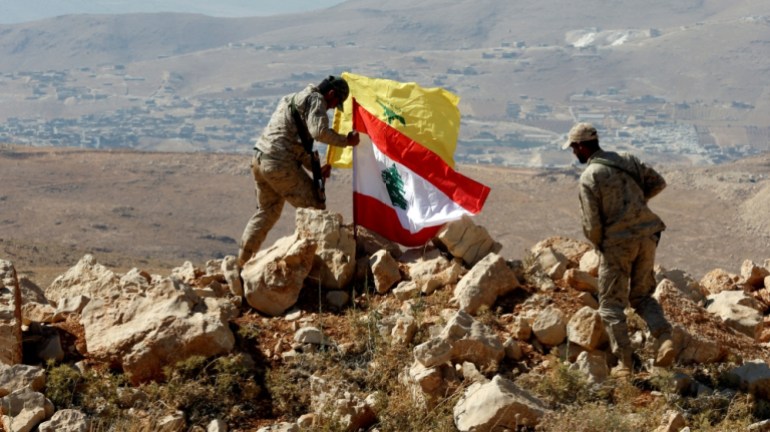 Hezbollah fighters put Lebanese and Hezbollah flags at Juroud Arsal, Syria-Lebanon border