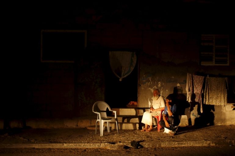 Palestinians sit outside their house as they flee the heat during power cut at Shatti (beach) refugee camp in Gaza City