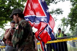 A white supremacists carries the Confederate flag as he arrives for a rally in Charlottesville Virginia
