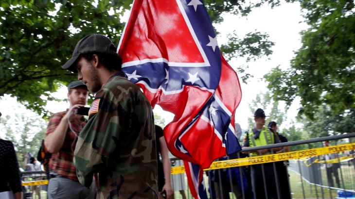 A white supremacists carries the Confederate flag as he arrives for a rally in Charlottesville Virginia