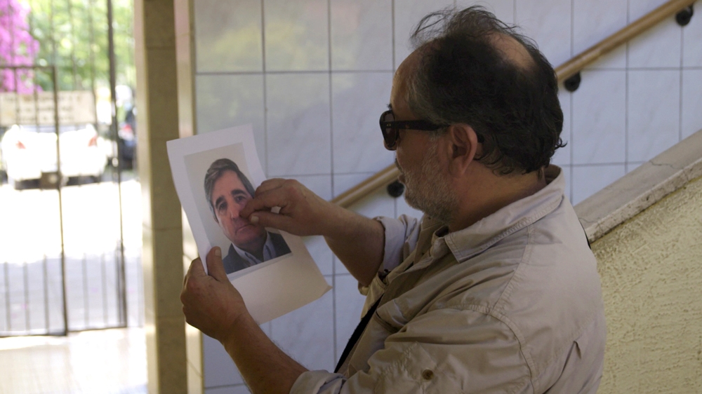 Jorge Lubbert in Barrio Olimpico, Santiago de Chile, holding a photo of Jose Pavez Ahumada [Screengrab/Al Jazeera]