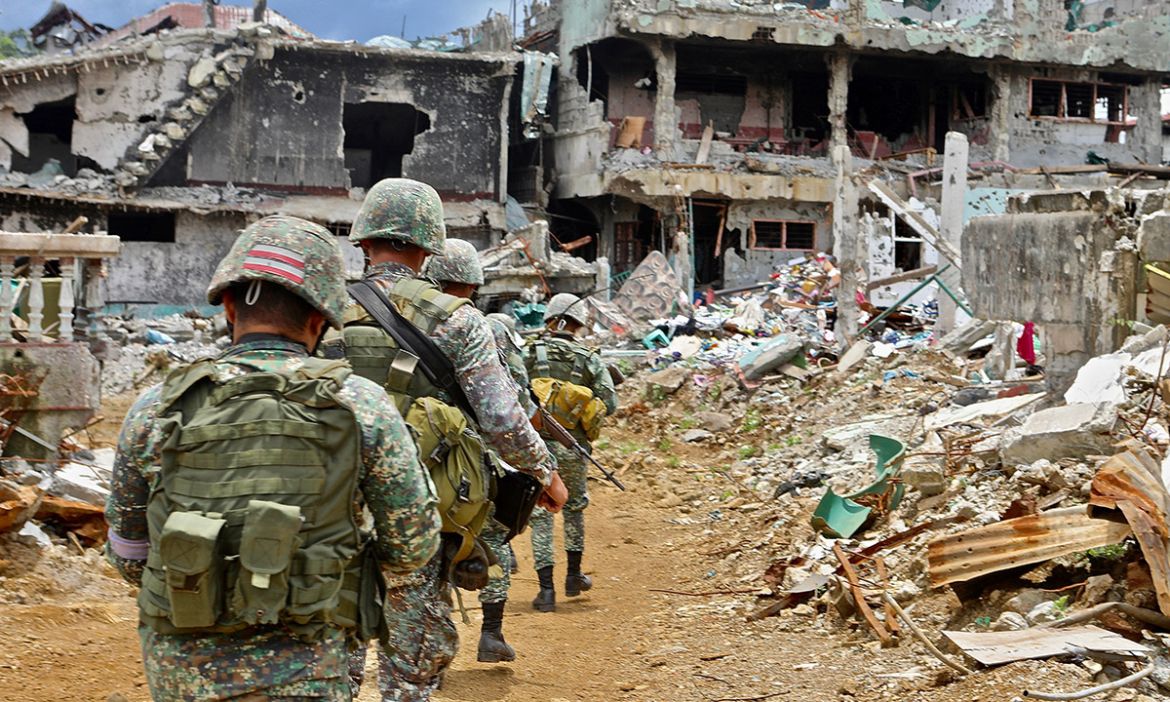 A platoon of Philippine soldiers patrols through the wreckage of downtown Marawi. Months of aerial and ground bombardment between the government and ISIL forces have reduced the city to rubble.