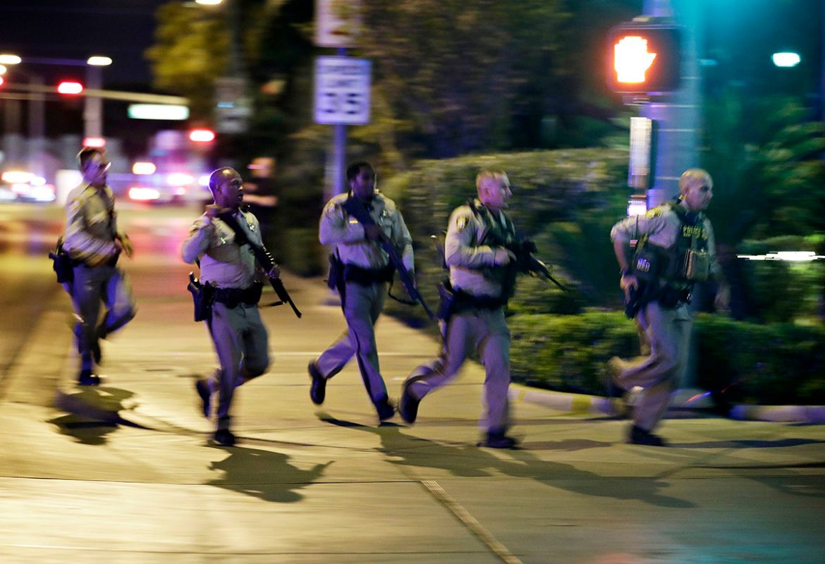 Police run to cover at the scene of a shooting near the Mandalay Bay resort and casino on the Las Vegas Strip, Sunday, Oct. 1, 2017, in Las Vegas. Multiple victims were being transported to hospitals