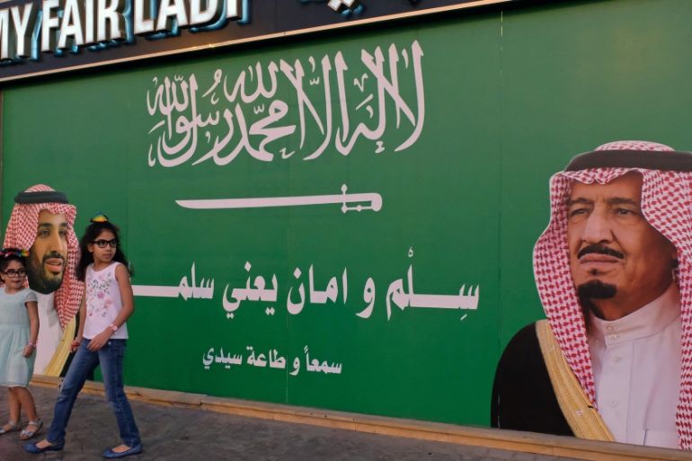 Girls stand next to a poster depicting Saudi Arabia''s King Salman bin Abdulaziz Al Saud and Crown Prince Mohammed bin Salman in Jeddah