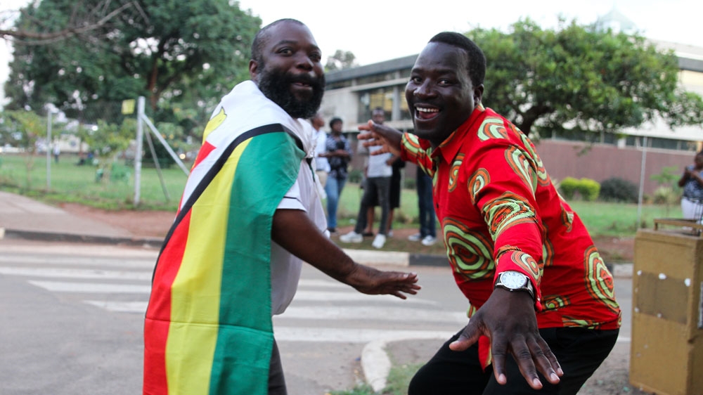 Victor Chifodya, with his friend Justin Mwanambu, dance in celebration [Tendai Marima/Al Jazeera] 