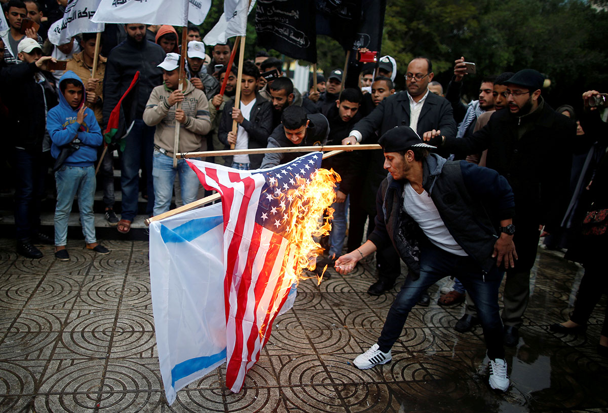 Palestinians burn Israeli and US flags during a protest against the US intention to move its embassy to Jerusalem and to recognise the city as the capital of Israel, in Gaza City [Mohammed Salem/Reuters]