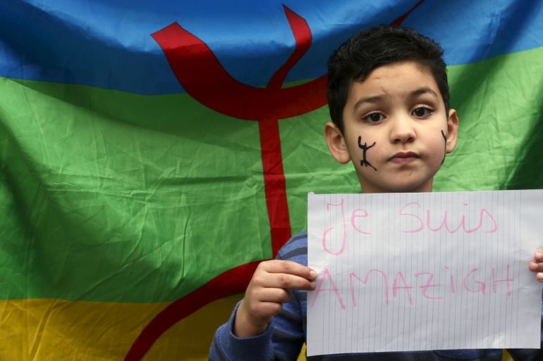 Boy holds a placard in front of an Amazigh flag during a demonstration in front of the Brussels'' office of Flemish right-wing party N-VA