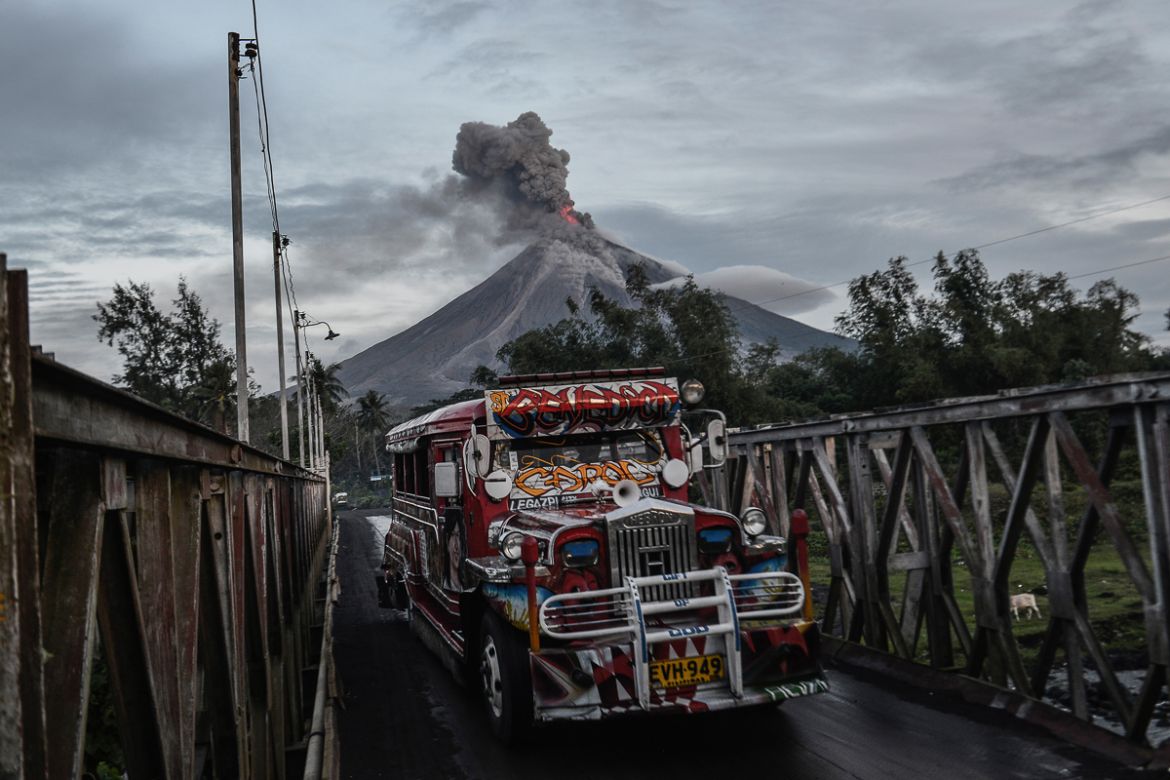 A jeepney crosses a bridge as Mount Mayon makes a mild eruption in Daraga, Albay province, Philippines, January 25, 2018.