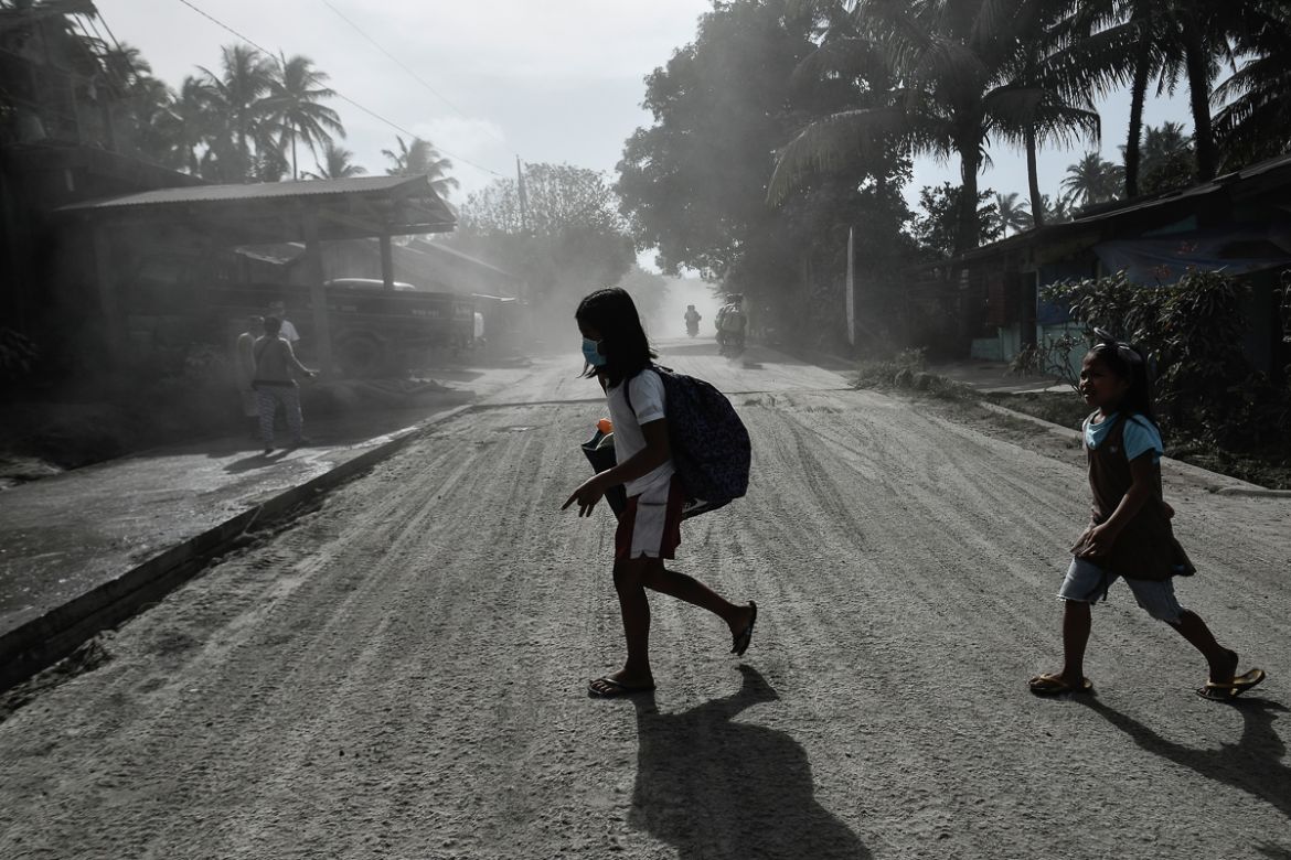 Children cross a road covered in thick ash inside the nine kilometer extended danger zone around Mount Mayon in Guinobatan, Albay province, Philippines, January 23, 2018.